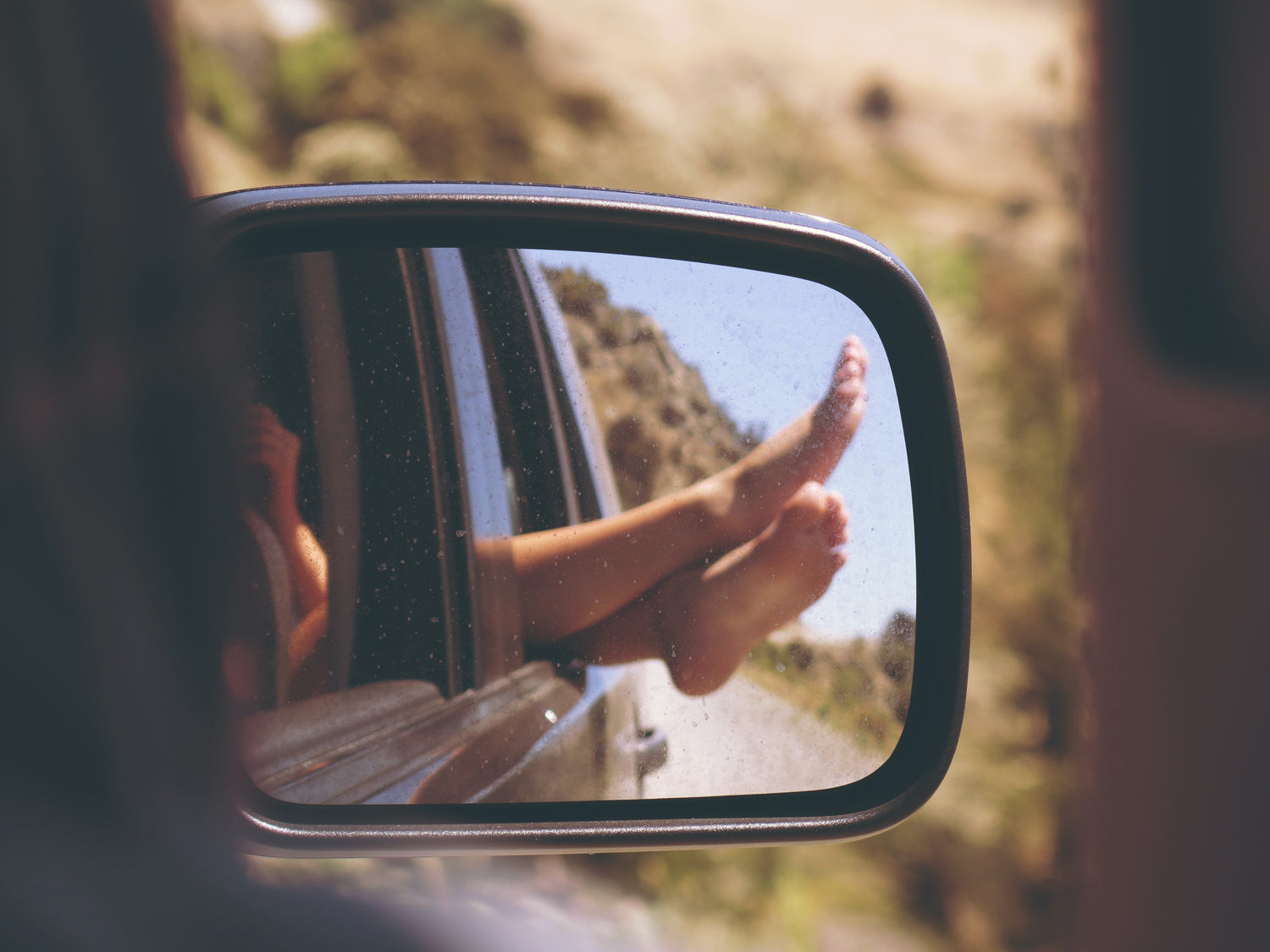 woman with her feet sticking out of the car window