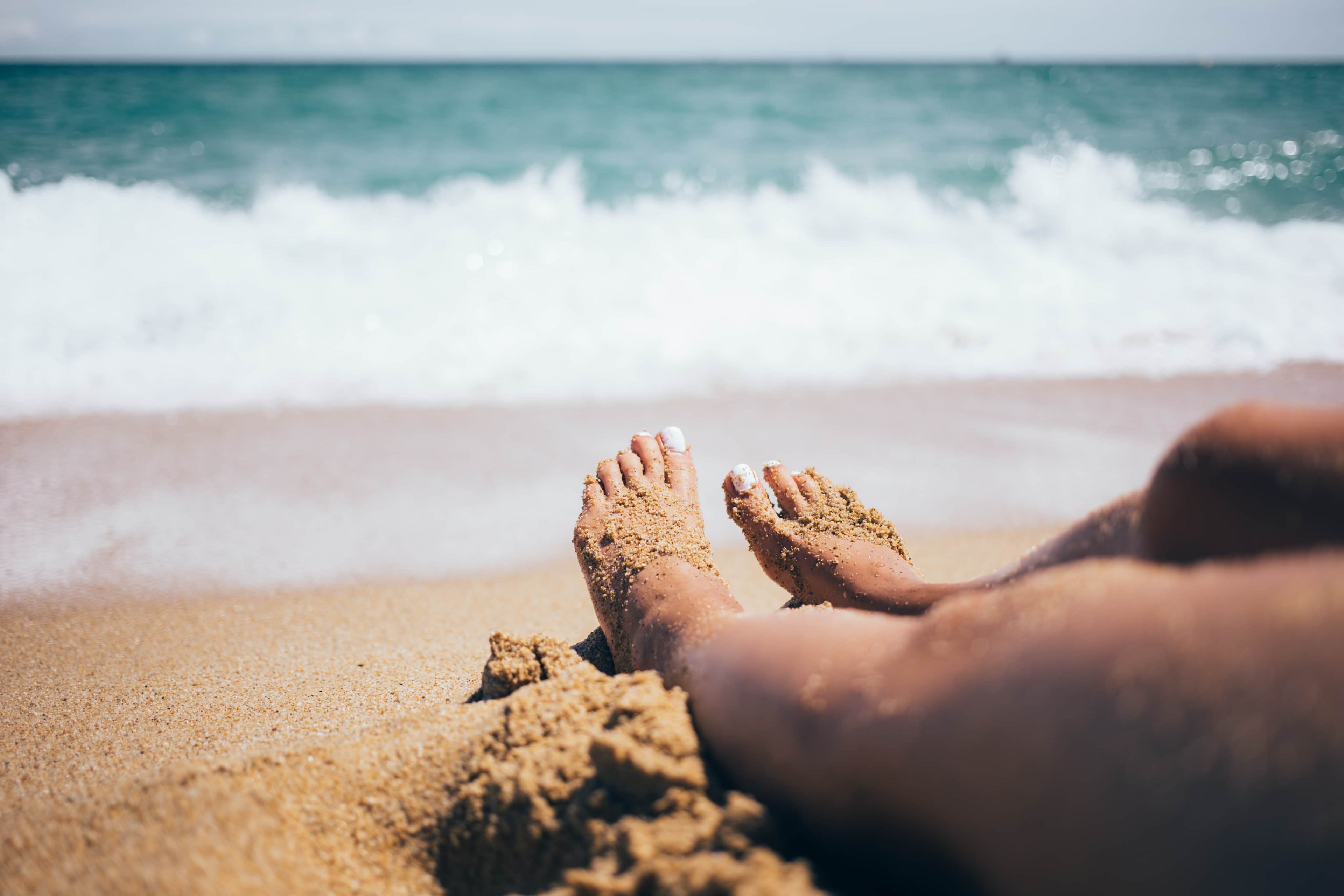 woman with her feet in the sand at the beach