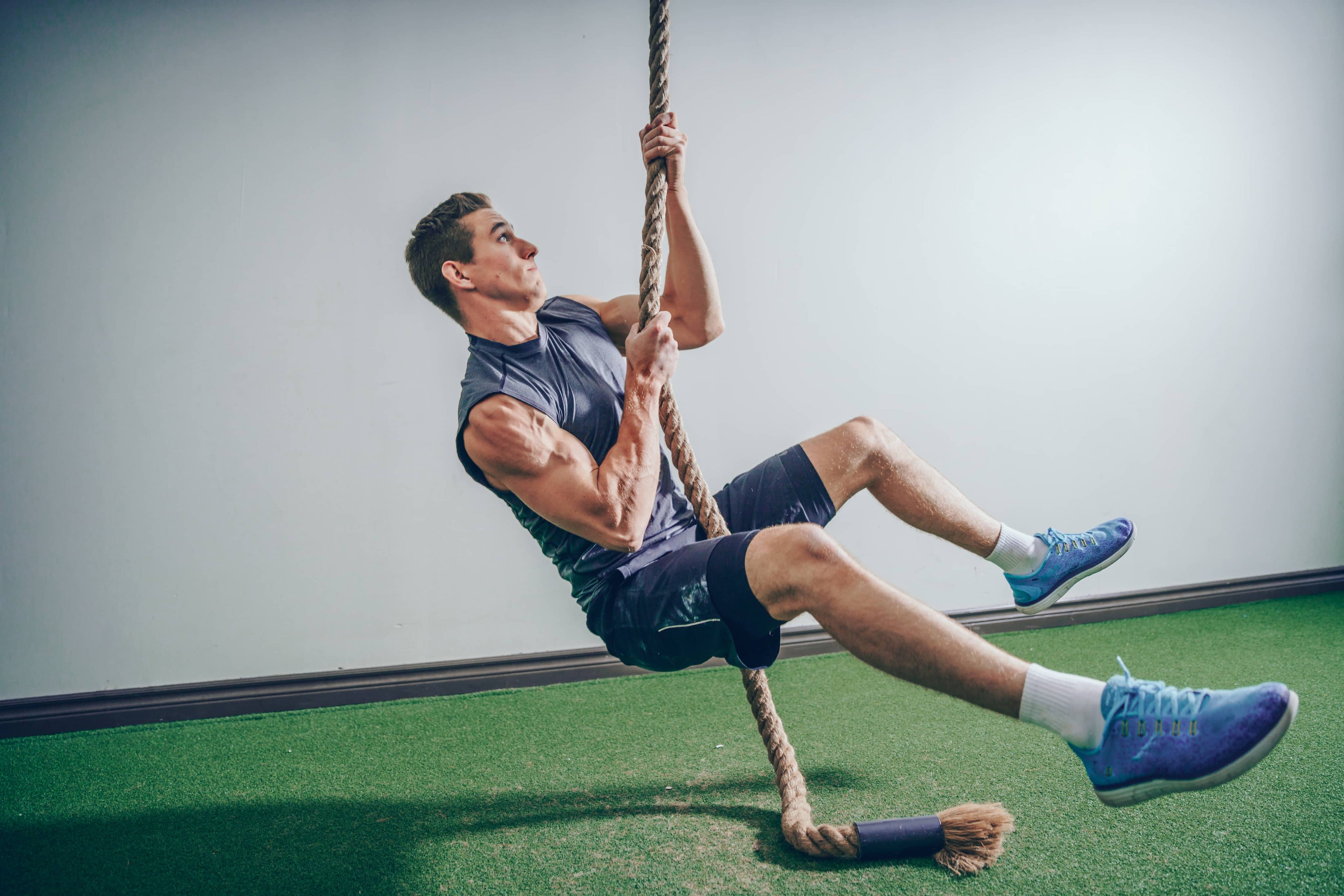 Fit man climbing crossfit rope